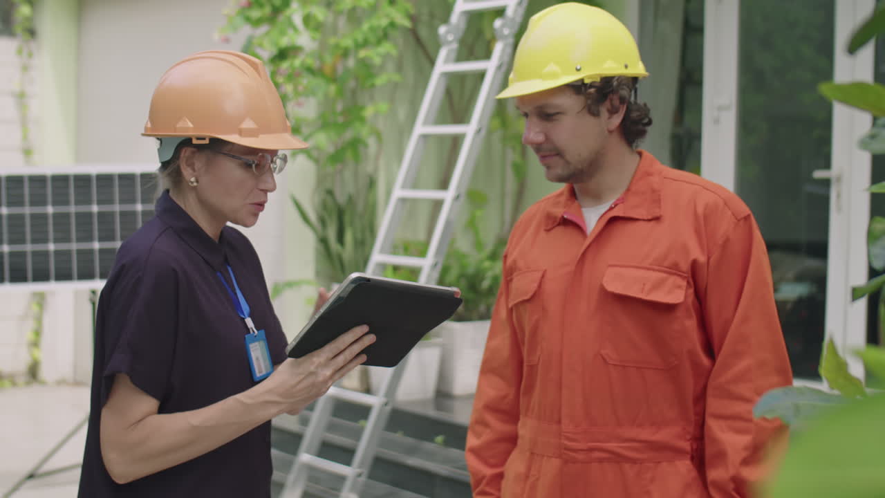 Female Engineer Instructing Worker about Solar Panels Installation
