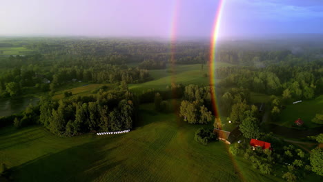 aerial drone shot flying high over a small village with houses and cottages along with green farmlands on a cloudy day