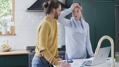 Caucasian-couple-in-a-modern-home-kitchen,-with-copy-space,-paying-bills