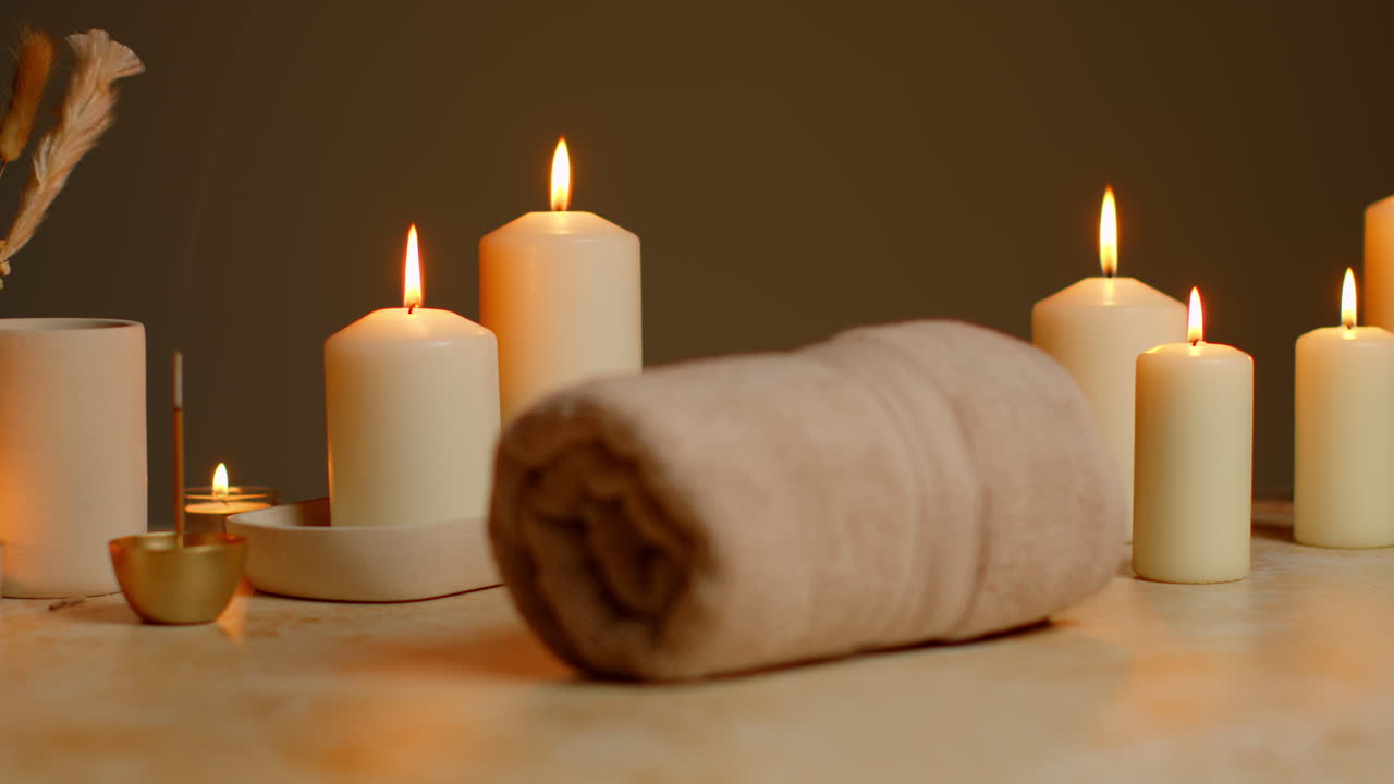 vida muerta de velas encendidas con hierbas secas, incienso y toallas suaves como parte de la relajante decoración del día de spa.