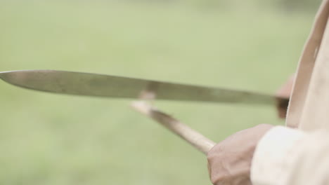 slow motion close footage of a person chopping on a stick to make a spear