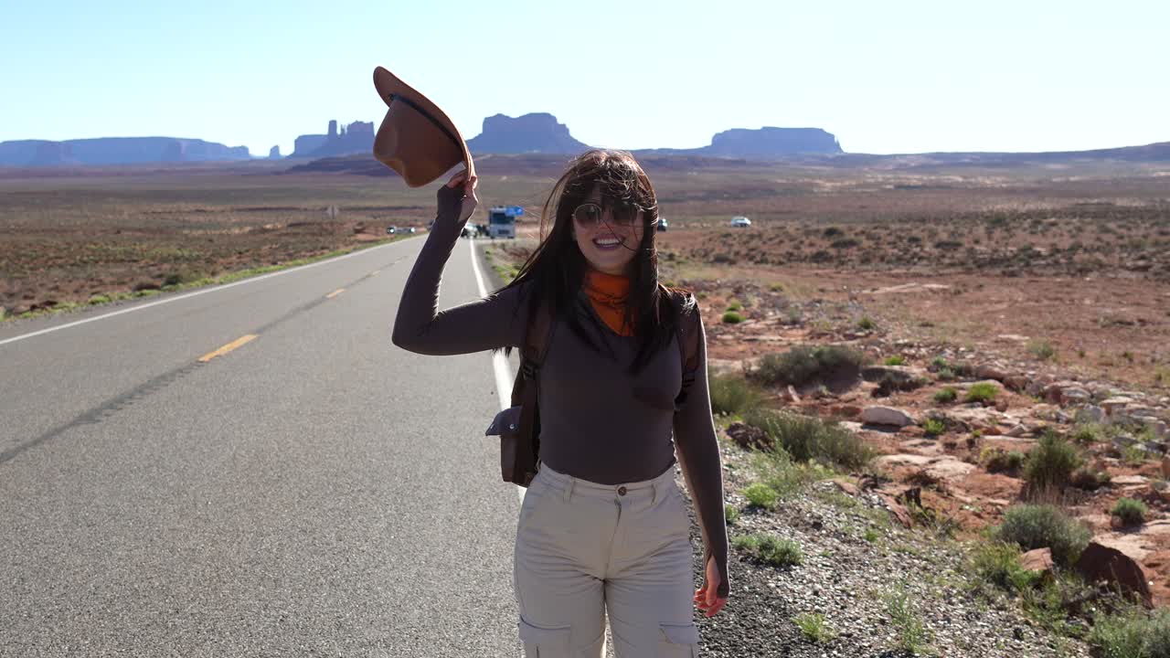 Glad kvinde går på ørkenvej mod Monument Valley
