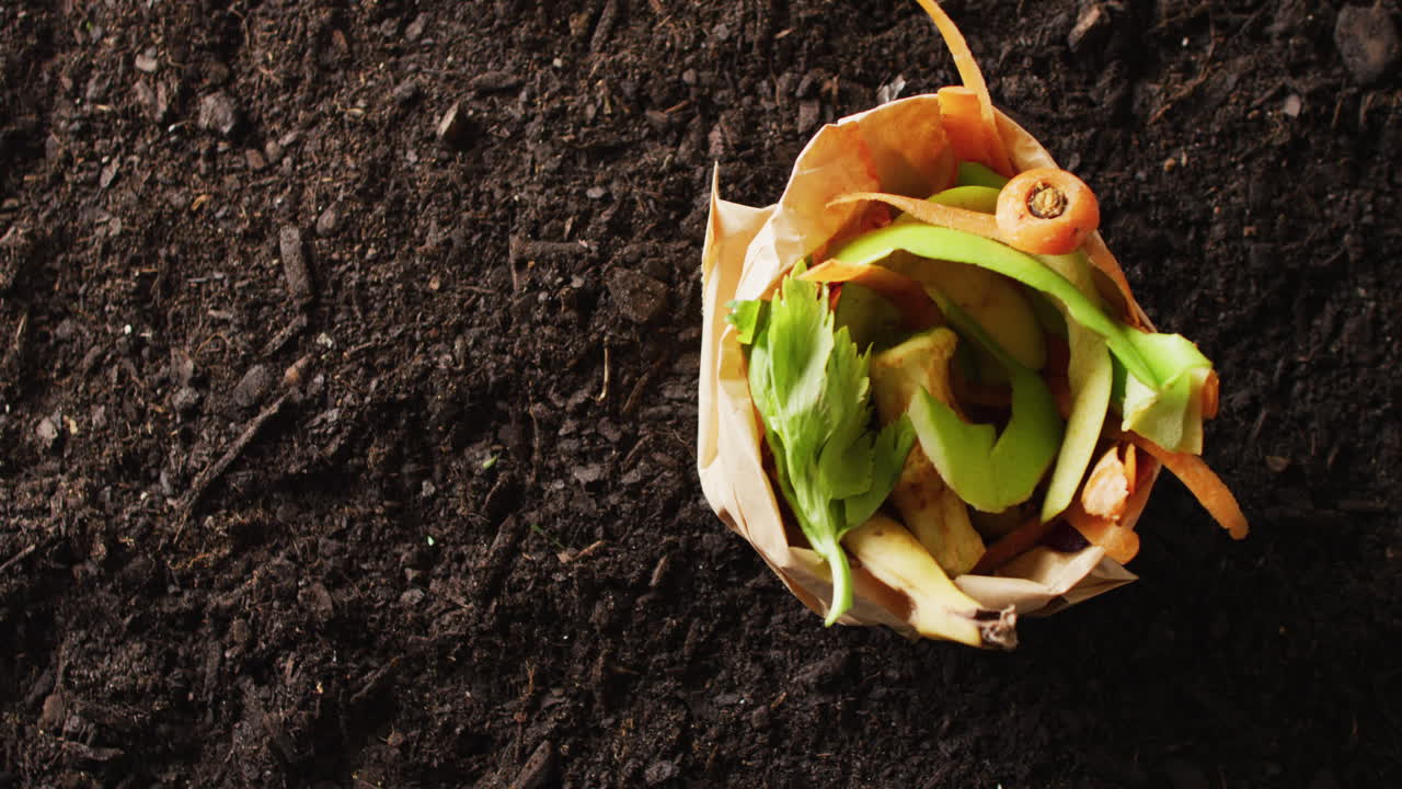 vídeo de una bolsa de residuos de frutas y hortalizas orgánicas para compostaje, en suelo oscuro con espacio para copiar
