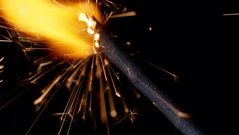 Bengal-fire,-New-Year-sparkler-candle,-sparkling-lights-burning-on-black-background,-close-up-macro