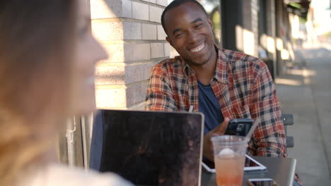 mixed race couple talking at a table outside a coffee shop