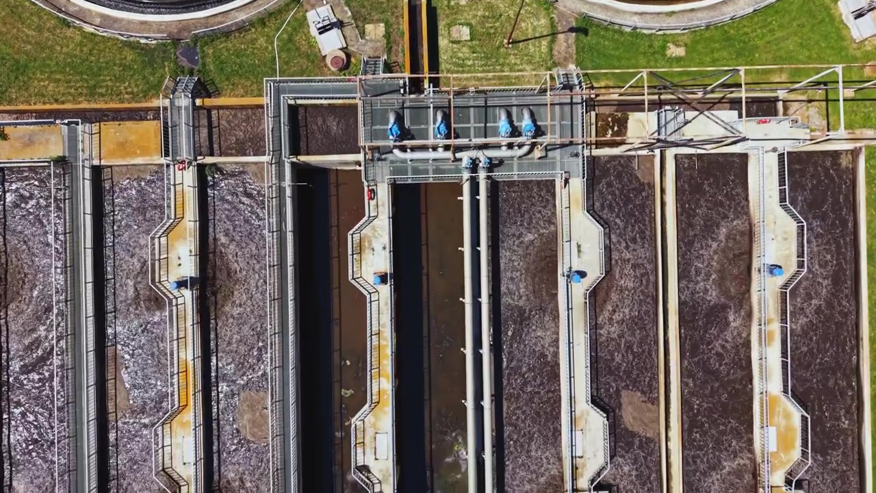 Wastewater plant with tanks and pipelines. Industrial water treatment facility from drone perspective. Aerial view of sewage processing center with clarifiers and aeration units