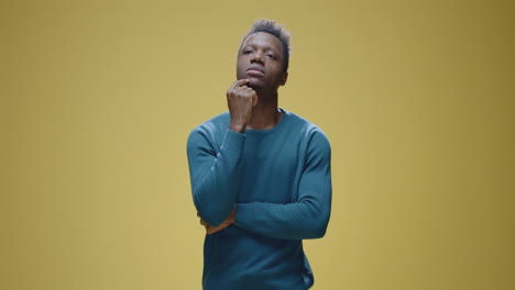 young african american man thinking and reflecting on yellow background
