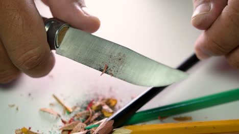 Footage-of-hands-slowly-sharpening-a-pencil-and-some-coloured-pencils-with-a-sharp-knife