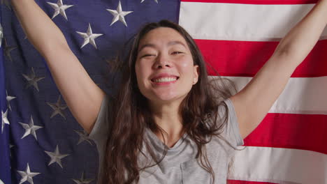 studio portrait shot of woman wrapped in american flag celebrating 4th july independence day 2