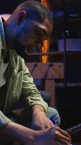 vertical video black freelancer taking notes on his textbook in order to solve his tasks
