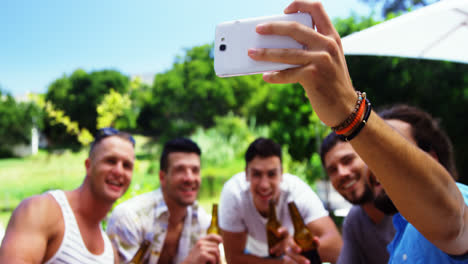 mujeres sonrientes usando el teléfono móvil mientras descansan junto a la piscina
