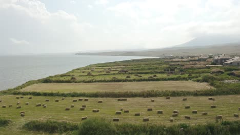 truck parked on farm fields with haystacks and rolls on shore of paravani lake in georgia