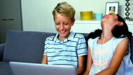 Siblings-having-fun-on-sofa-in-living-room