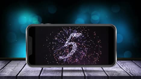 animation of fireworks exploding with glowing countdown to midnight displayed on smartphone screen o