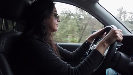 hispanic woman driving car on road through countryside, road trip