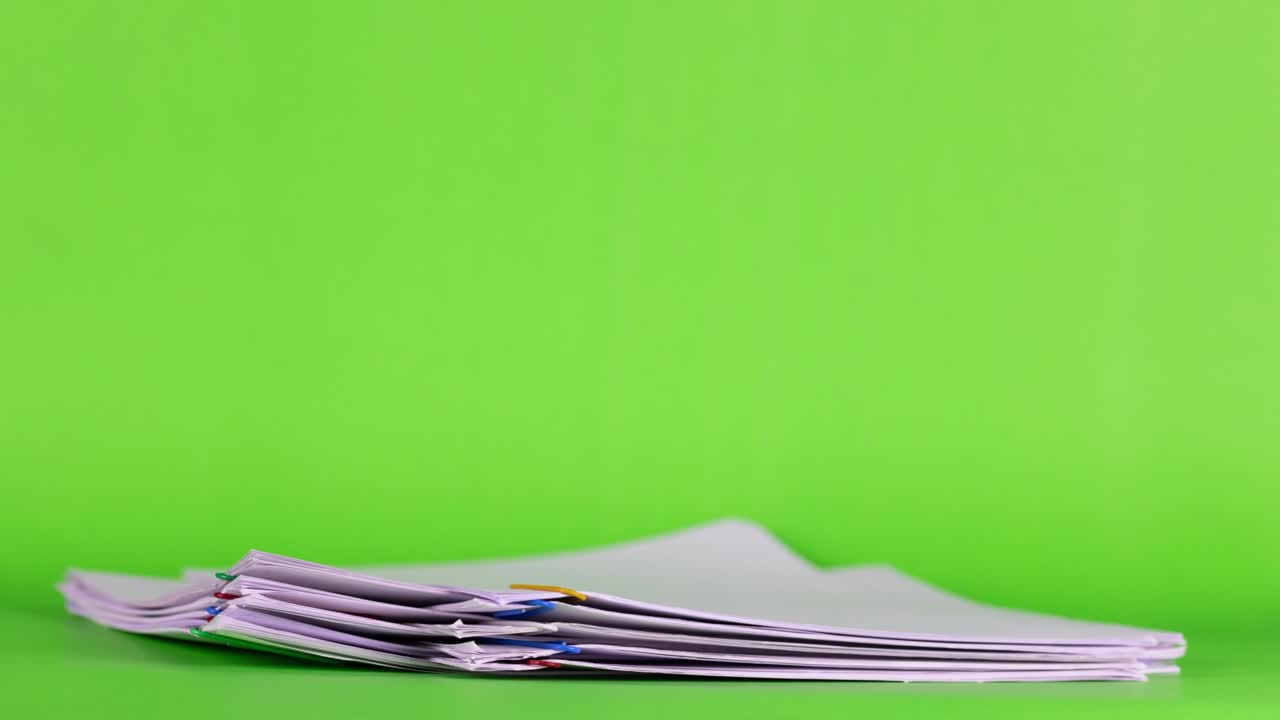 papel de informe de documento de sobrecarga de pila de movimiento de 4k con clips de papel coloridos en fondo verde y espacio de copia, imágenes de concepto de negocio sin papel utilizadas.