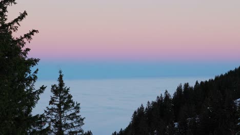 drone footage capturing the serene beauty of sunrise over the majestic silhouette of a snowy mountain range