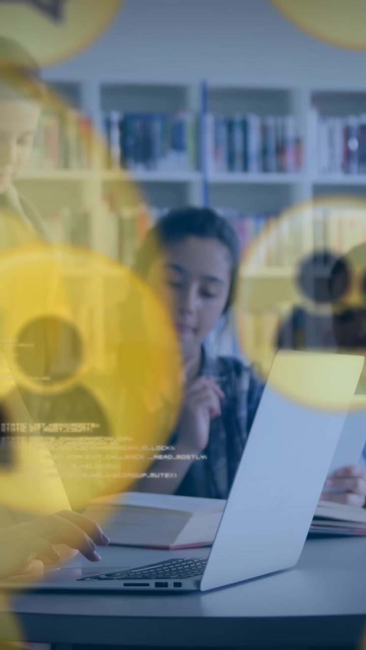 Vertical video: Teen girl typing pausing, causing yellow icons shifting over laptop during study