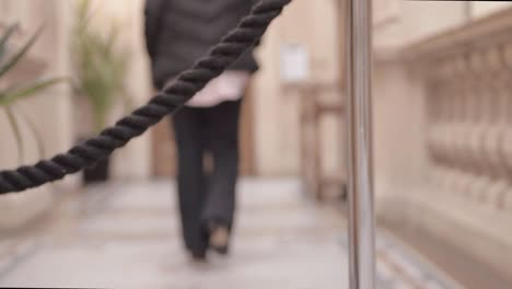 Person-walking-away-from-event-rope-stanchion-in-lobby