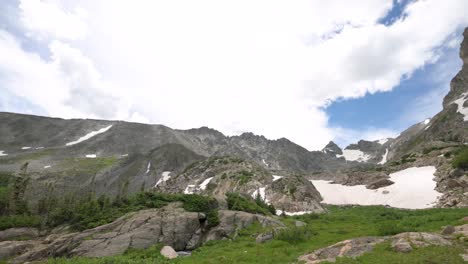 Storm-clouds-over-snow-covered-Rocky-Mountains-with-pine-trees-during-the-day,-static