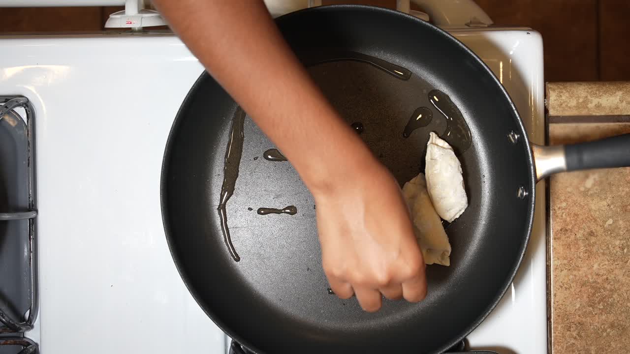 Placing Japanese gyoza dumplings in an oiled frying pan - overhead view