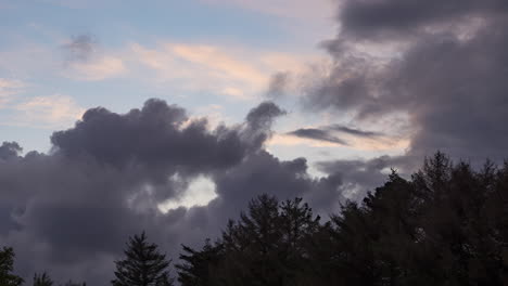 sunset time lapse, dark clouds roll in and cover colorful sky over forest