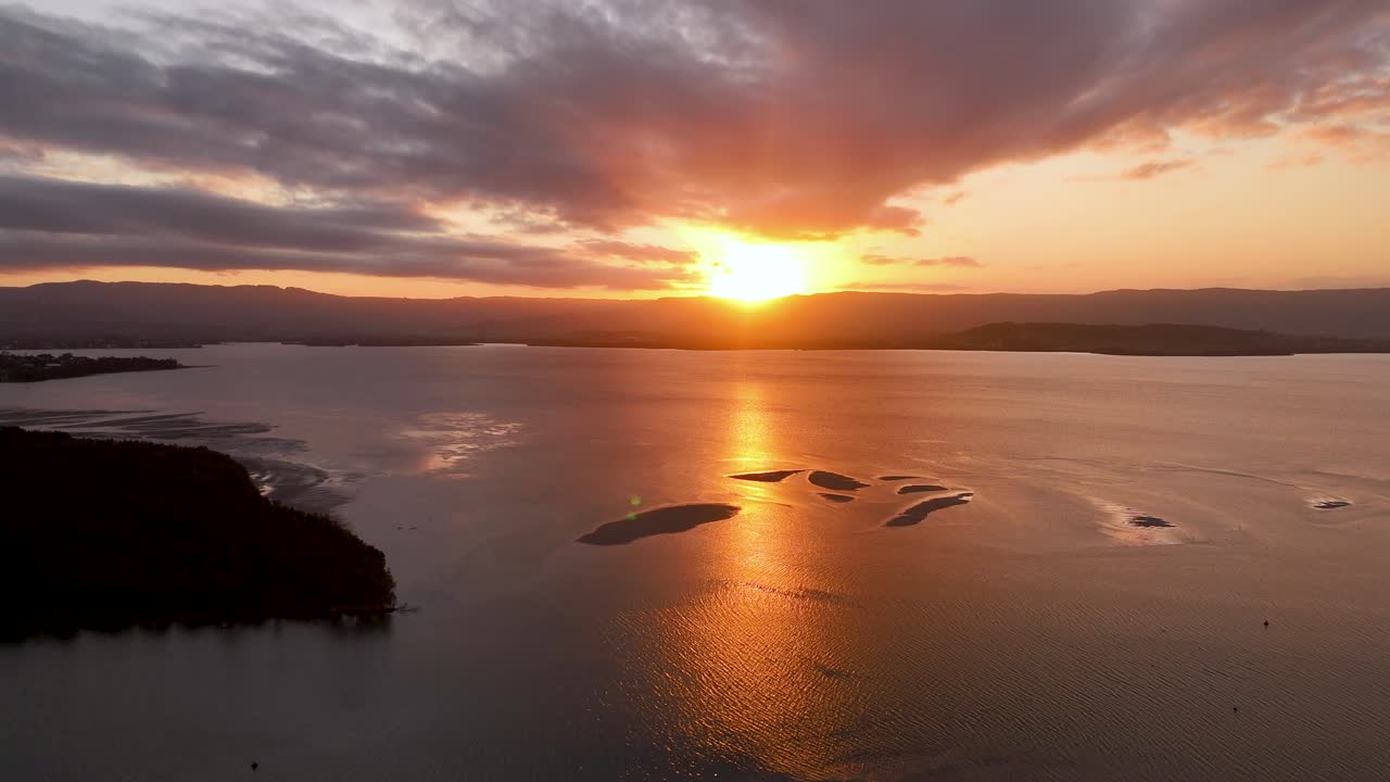Ilmakuva upeasta auringonlaskusta tyynen järven yllä