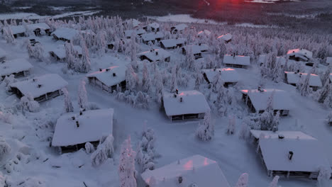 Descripción-Aérea-De-Refugios-De-Montaña-En-La-Cima-De-Un-Fjell-Nevado,-Amanecer-En-Laponia