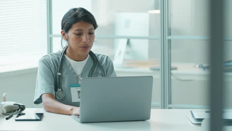doctora hispana trabajando en una computadora portátil en la clínica