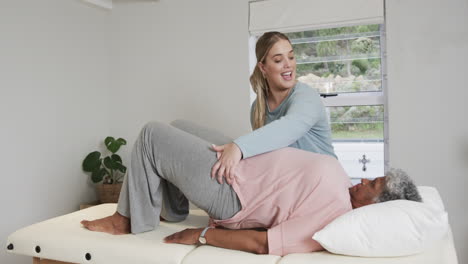 caucasian female physiotherapist massaging senior woman, copy space, slow motion