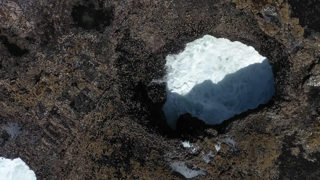 Static shot of ocean waves splashing and rising from underwater cave on the California coast.