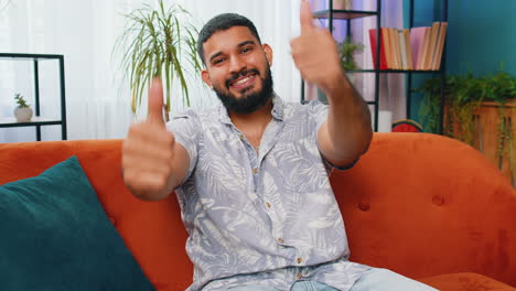 joven indio feliz mirando con aprobación a la cámara muestra los pulgares hacia arriba como un signo positivo buenas noticias