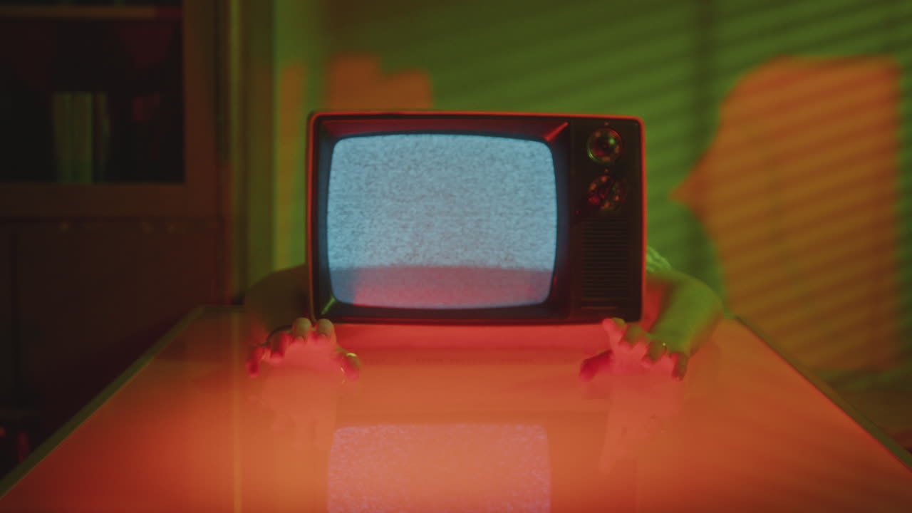 Retro Analog TV with Human Hands Tapping Their Fingers on Illuminated Table