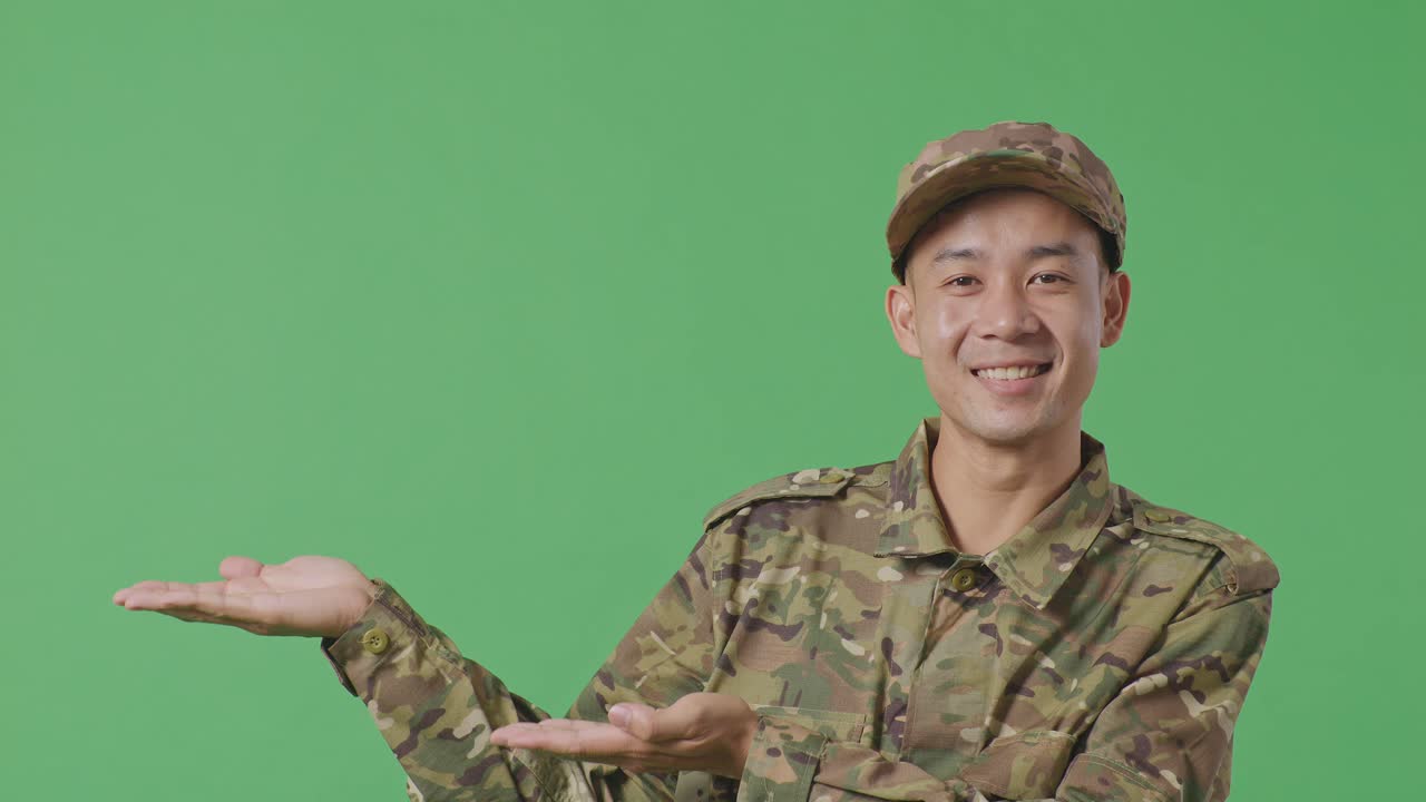 Close Up Of Asian Man Soldier Smiling And Pointing To Side While Standing In The Green Screen Background Studio