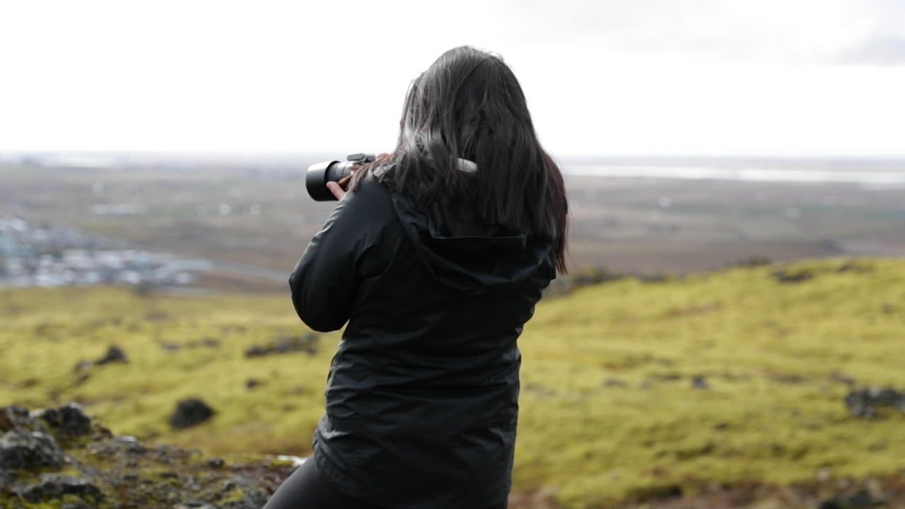 chica sosteniendo una cámara tomando fotos del paisaje de islandia en cámara lenta
