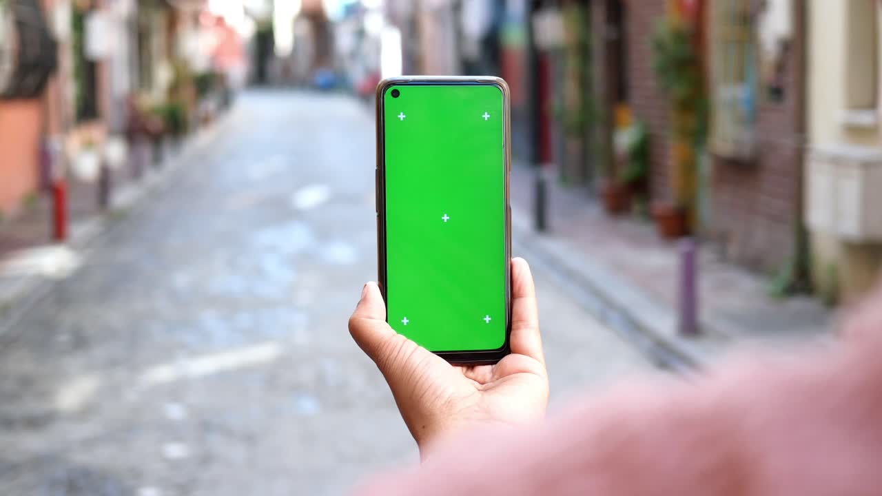 persona con un teléfono de pantalla verde en una calle de la ciudad