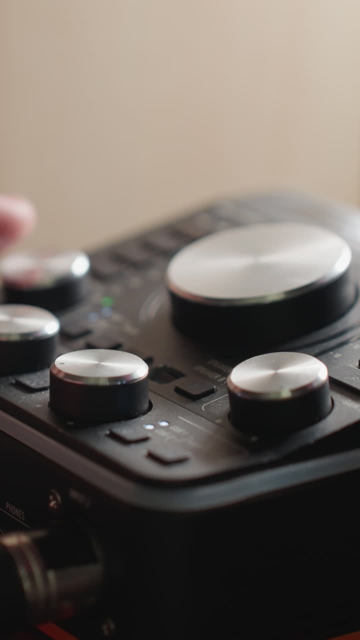 primo piano di una mano che aziona un mixer sonoro, regolando le manopole per regolare i livelli audio. mostra l'interazione tattile con i comandi del mixer