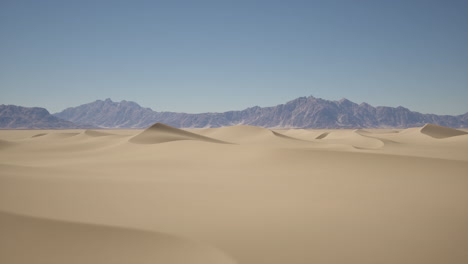 dunas de arena en el desierto con montañas en el fondo