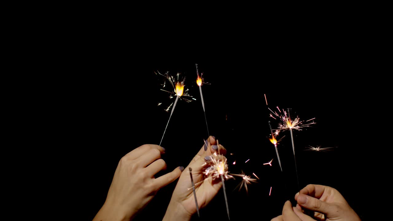 Hands holding and waving Bengal fires. New year sparkler candle burning on a black background