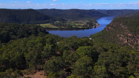 dramatic high view over trees and bushes to a winding blue river with blue sky and white clouds