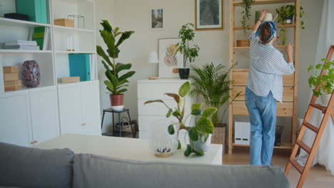 woman dancing and watering flowers in living room