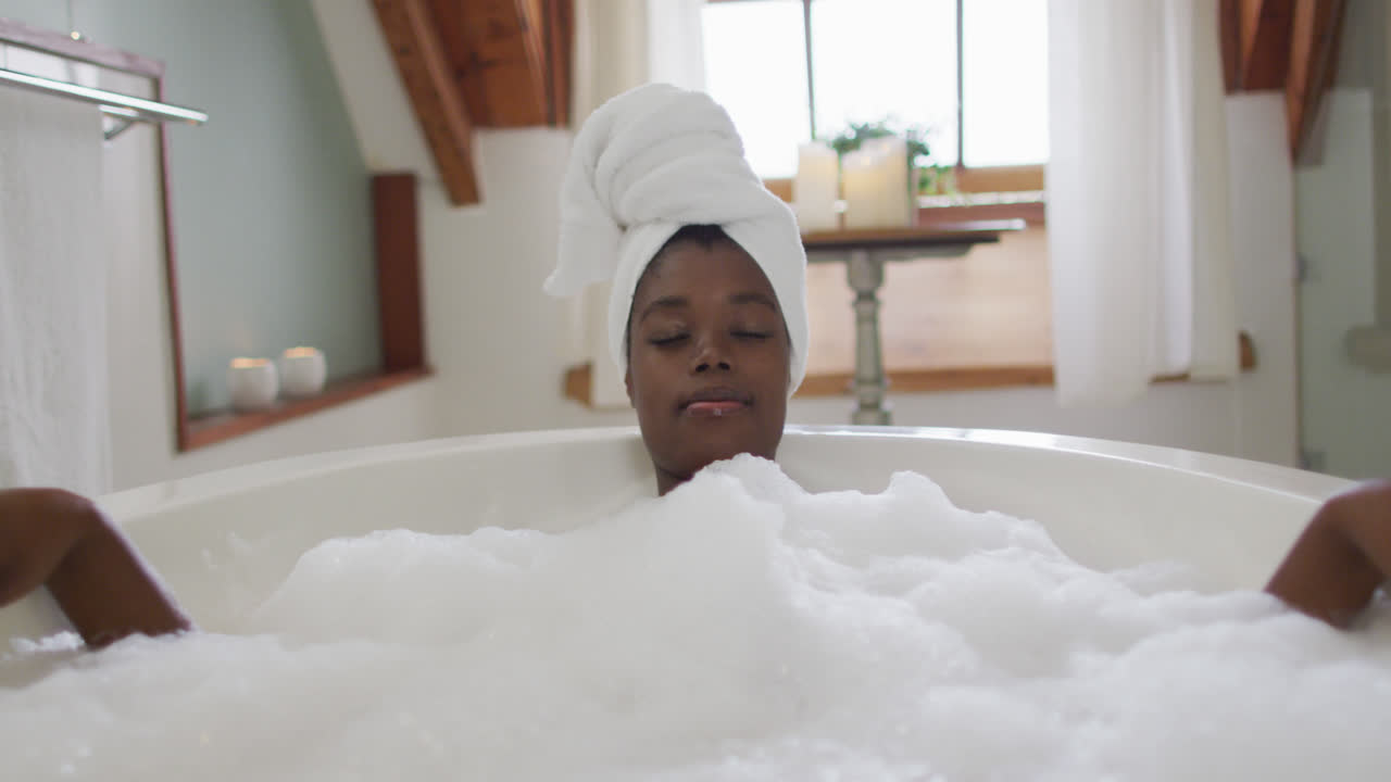 African american attractive woman relaxing in foam bath in bathroom