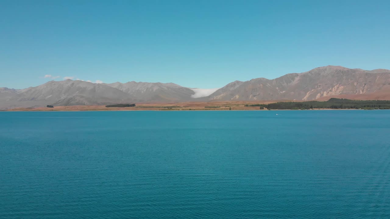 toma aérea del lago tekapo, nueva zelanda y su hermosa agua azul turquesa con montañas en el fondo