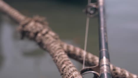 vieja cuerda marrón con caña de pescar sobre el agua en un barco de madera