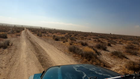 vehículo con tracción en las cuatro ruedas sale de un camino pavimentado hacia un camino de tierra en el desierto de mojave para un viaje aventurero - punto de vista del conductor