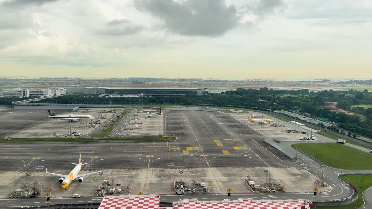 Pesawat jet penumpang mendarat melewati lapangan golf hijau menuju landasan pacu yang ramai di bawah langit sore yang berawan