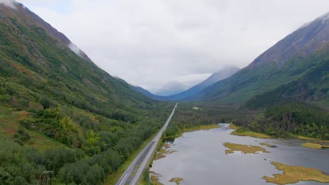 experience a smooth horizontal pan aerial shot at tern lake pullover, alaska, capturing the serene lake, highway, and majestic mountains. perfect for travel, landscape, or outdoor adventure content.