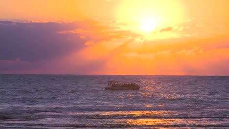 a fishing boat heads into the sunset on the mediterranean sea