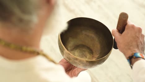 senior man playing bowl gong with mallet