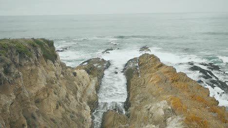 Slow-Motion-waves-coming-in-over-coastal-bluffs-on-overcast-summer-day